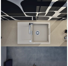 Évier à encastrer en composite de quartz beige avec un bac, égouttoir et robinet chromé dans une cuisine moderne, vue de dessus.