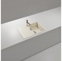 Évier à encastrer beige avec égouttoir et robinet chromé, intégré dans un plan de travail blanc avec façade à lattes.