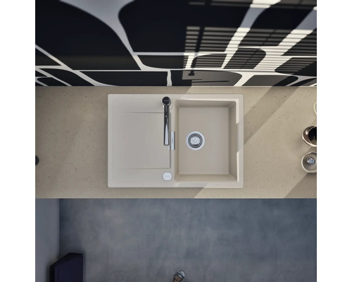 Évier de cuisine moderne avec égouttoir et robinet dans un plan de travail clair, associé à un mur à motifs dans une cuisine lumineuse.