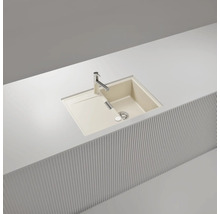 Évier à encastrer beige en composite de quartz avec un bac, un égouttoir et un robinet, encastré dans un plan de travail blanc.