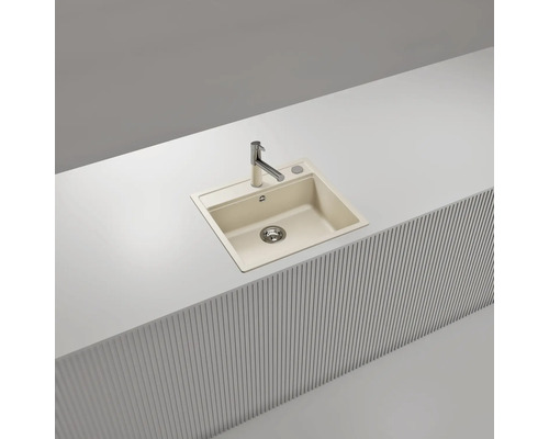 Évier de cuisine encastrable en composite beige avec robinet chromé, installé dans un plan de travail blanc.