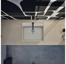 Évier de cuisine moderne avec mitigeur monocommande, vue de dessus sur un plan de travail aspect pierre devant un mur à motifs.