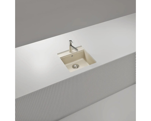 Évier à encastrer en composite de quartz avec robinet de cuisine chromé, intégré dans un plan de travail clair.