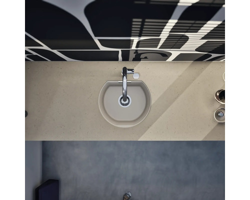 Vue de dessus d'un évier de cuisine en composite beige dans un plan de travail assorti avec un robinet chromé.
