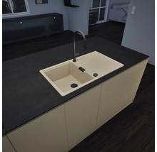 Îlot de cuisine moderne avec évier beige en matériau composite, égouttoir et robinet noir à bec haut. Plan de travail sombre.