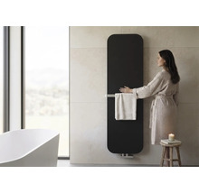 Radiateur de salle de bains vertical avec porte-serviettes dans une salle de bains moderne avec baignoire en îlot et femme en peignoir.