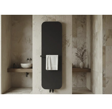 Radiateur vertical plat moderne dans une salle de bains avec murs en pierre, vasque et porte-serviette avec serviette blanche.