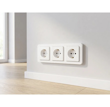 Dreifach-Steckdose horizontal an einer Wand über einer Sockelleiste in einem modernen Raum mit Holzboden.