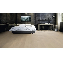 Chambre à coucher moderne avec parquet clair, un lit double avec du linge de lit blanc et un mur sombre texturé.