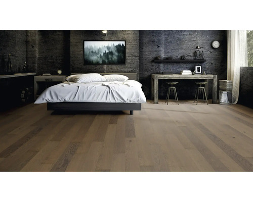 Parquet en lames larges dans une chambre à coucher moderne avec des murs en béton sombre et des meubles industriels.