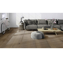 Salon moderne avec parquet aspect chêne, canapé gris et table en bois clair dans une pièce lumineuse.