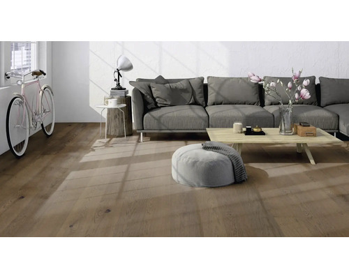 Salon moderne avec parquet aspect chêne, canapé gris et table en bois clair dans une pièce lumineuse.