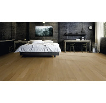 Chambre moderne avec un parquet en bois clair, des murs sombres en aspect béton, un lit double et un bureau en bois.
