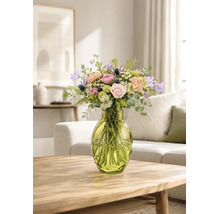 Farbenfroher Blumenstrauß mit Rosen und Eukalyptus in einer grünen Glasvase auf einem Holztisch in einem hellen Wohnzimmer.