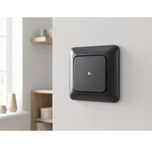 Mattschwarze quadratische Abdeckung mit Zentralschraube an einer Wand montiert in einem hellen, modern eingerichteten Raum.