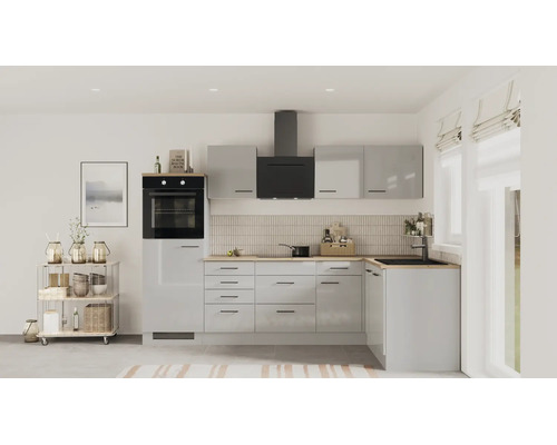 Cuisine moderne en L avec façades gris clair brillantes, plan de travail en bois, four noir et hotte aspirante dans une pièce lumineuse.
