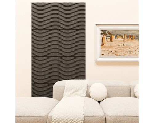 Wohnzimmer mit dunkel strukturierter Wandpaneele in Wellenoptik. Daneben ein helles Sofa mit Dekokissen und Decke sowie ein gerahmtes Bild an der Wand.