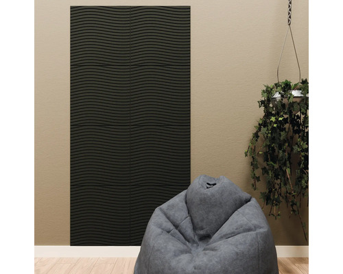 Panneau acoustique noir avec structure ondulée horizontale sur un mur beige, combiné avec un pouf gris et une plante suspendue.