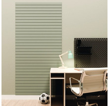 Un panneau mural vert à lattes horizontales à côté d'un bureau avec chaise de bureau et un panneau perforé noir.