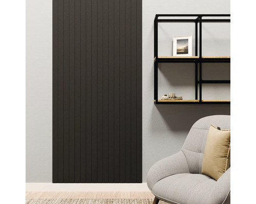 Panneau mural sombre à lamelles verticales dans un salon moderne à côté d'une étagère noire et d'un fauteuil.