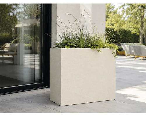 Grande jardinière rectangulaire avec des plantes vertes sur une terrasse moderne.