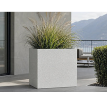 Grand bac à fleurs carré avec surface structurée et graminées sur une terrasse moderne.