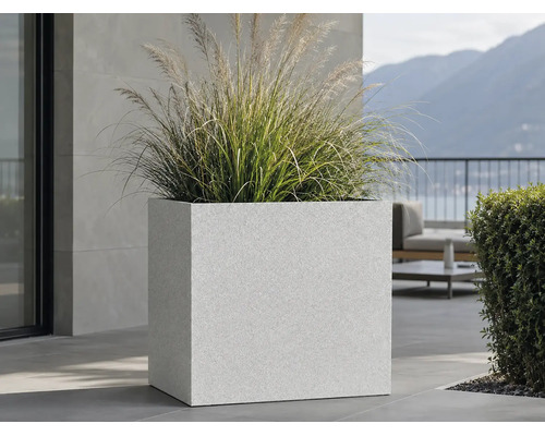 Grand bac à fleurs carré avec surface structurée et graminées sur une terrasse moderne.