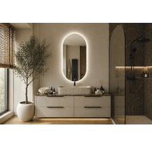 Salle de bains moderne et lumineuse avec miroir ovale rétroéclairé, vasque à poser cannelée sur meuble et douche à l'italienne noire.
