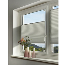 Weißes Plissee an einem Fenster montiert, davor stehen dekorative Vasen auf der hellen Fensterbank.