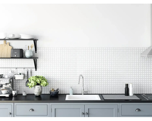 Cuisine moderne et lumineuse avec crédence à motifs géométriques, évier encastré blanc, robinet en chrome et meubles bas gris.