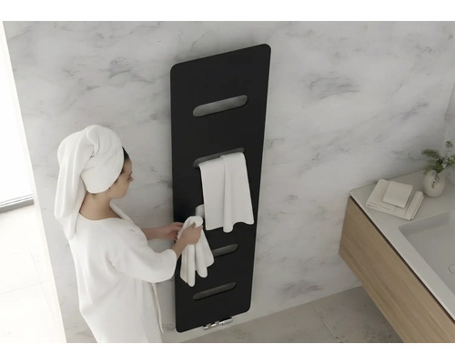 Sèche-serviette noir dans une salle de bain moderne avec mur en marbre. Une femme en peignoir suspend une serviette.