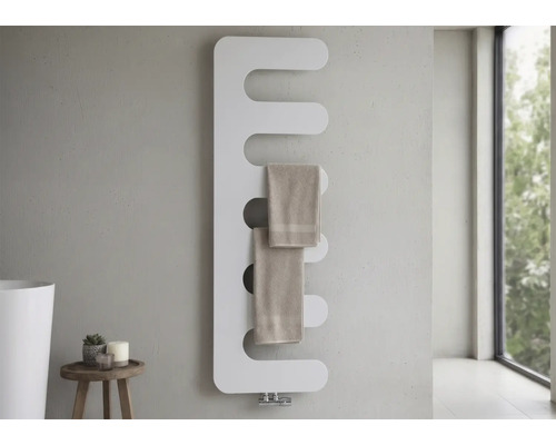 Radiateur de salle de bains moderne en forme de peigne avec des coins arrondis, monté sur un mur gris avec deux serviettes.