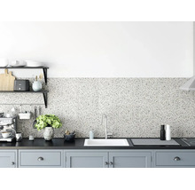 Fond de hotte aspect terrazzo dans une cuisine moderne avec plan de travail sombre, évier blanc et éléments gris clair.