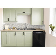 Cuisine moderne avec façades vert sauge, poignées noires, crédence effet terrazzo, évier en inox et plan de travail aspect bois.