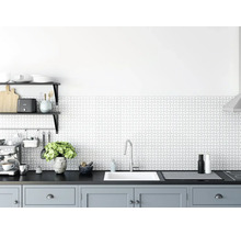 Cuisine moderne et lumineuse avec crédence à motifs géométriques, évier encastré blanc, robinet en chrome et meubles bas gris.