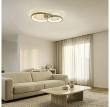 Moderne LED-Deckenleuchte mit zwei ineinandergreifenden Ringen in einem hellen, modern eingerichteten Wohnzimmer mit Sofa und Couchtisch.
