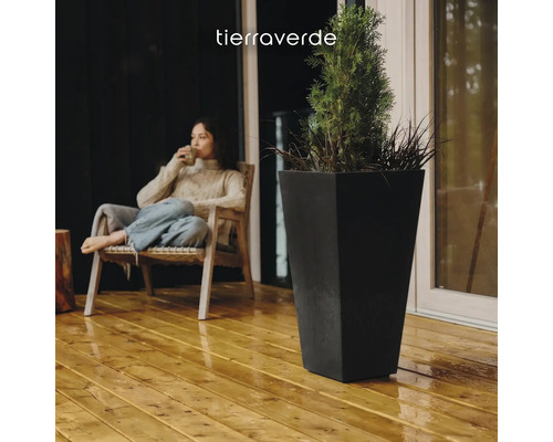 Grand bac à fleurs carré et conique en noir sur une terrasse en bois avec une plante. Tierraverde Logo.