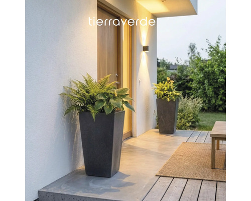 Deux grands pots de fleurs coniques aspect pierre avec des fougères et des hostas sur une terrasse moderne éclairée. Logo Tierraverde.