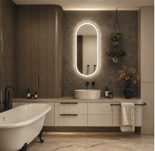 Salle de bains moderne avec baignoire en îlot, meuble sous-vasque à structure rainurée, vasque à poser et miroir LED ovale sur mur en marbre.