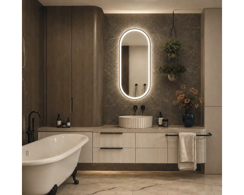 Salle de bains moderne avec baignoire en îlot, meuble sous-vasque à structure rainurée, vasque à poser et miroir LED ovale sur mur en marbre.