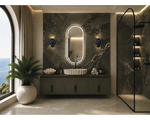 Salle de bains moderne avec mur en marbre vert, miroir ovale éclairé, vasque à poser blanche sur un meuble et douche à l'italienne.
