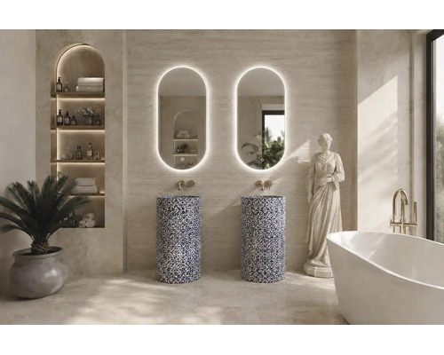 Salle de bain moderne avec deux lavabos colonnes en pierre à motifs, miroirs ovales rétroéclairés, baignoire îlot et robinetterie dorée.
