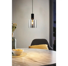 Moderne Pendelleuchte mit zylindrischem Glasschirm und schwarzer Metallfassung über einem Esstisch in Marmoroptik.