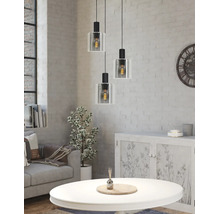 Dreiflammige Pendelleuchte mit Glasschirmen in hellem Wohnzimmer mit weißer Ziegelwand, Sofa und Couchtisch im Industrie-Stil.