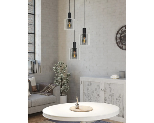 Dreiflammige Pendelleuchte mit Glasschirmen in hellem Wohnzimmer mit weißer Ziegelwand, Sofa und Couchtisch im Industrie-Stil.