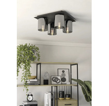 Vierflammige Deckenleuchte mit schwarzer Metallbasis und zylindrischen Schirmen aus Rauchglas in einem hellen Wohnraum mit Regal.