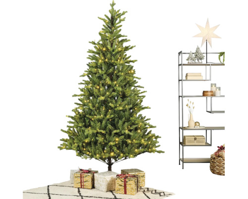 Künstlicher Weihnachtsbaum mit warmweißer LED-Beleuchtung, Geschenken und einem modernen Metallregal mit Weihnachtsdekoration auf einem Teppich.