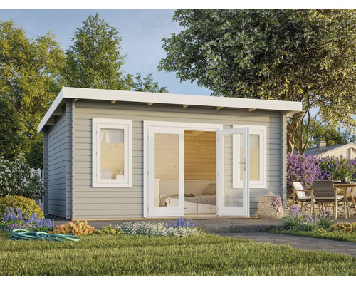 Abri de jardin moderne en bois gris avec toit en appentis, double porte blanche vitrée et fenêtre dans un jardin lumineux avec terrasse.