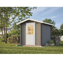 Abri de jardin gris en bois avec toit à deux pans blanc et porte blanche avec fenêtre à croisillons, situé dans un jardin avec une roue de charrette.