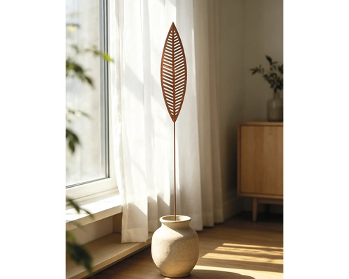 Gartenstecker aus Metall in Blattform mit Aussparungen und Rost-Optik, stehend in einer Steinvase vor einem hellen Fenster mit Vorhängen.